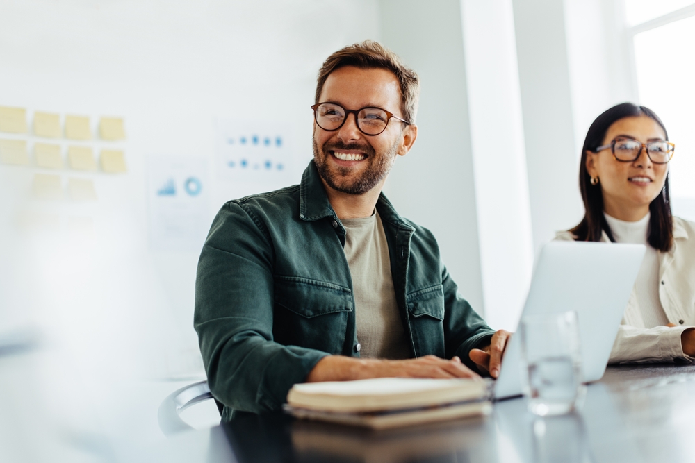 A confident man with a healthy smile sits in a business meeting, showcasing the professional benefits of Comprehensive General Dentistry at Wilder Dentistry