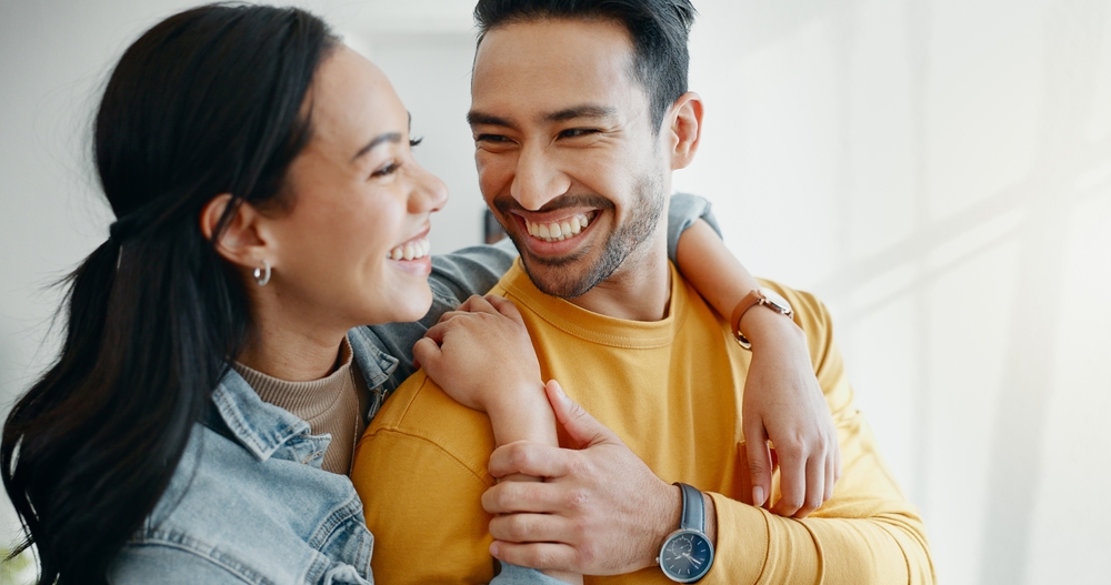 A happy man with a full, confident smile embraces his partner. Restore your complete smile with Dental Implants at Wilder Dentistry