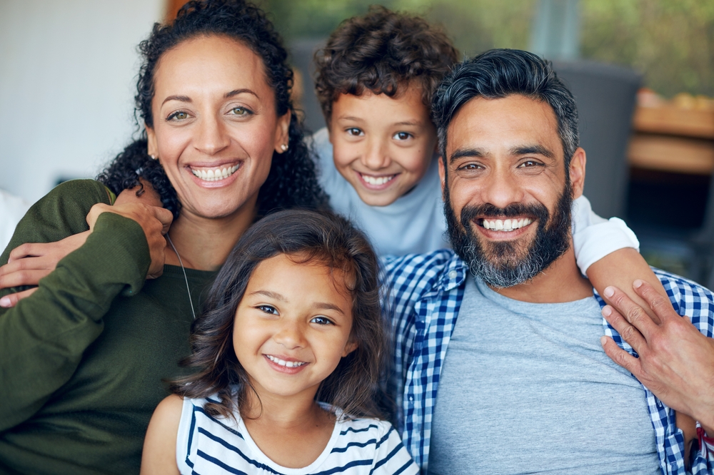 A relaxed and happy family of four smiling together for a portrait. If you feel anxious about dental visits, you can be this comfortable with gentle Sedation Dentistry at Wilder Dentistry